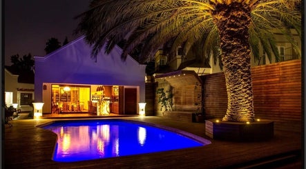Evening poolside view at Peau Aesthetics, Germiston, Gauteng, ZA with illuminated palm tree and elegant lounge.