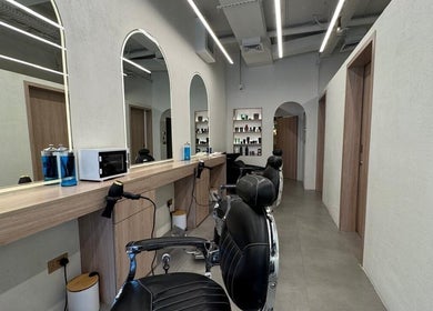 Modern interior of Black Oak Gents Salon in Dubai, Dubai, AE with stylish barber chairs and product shelves.