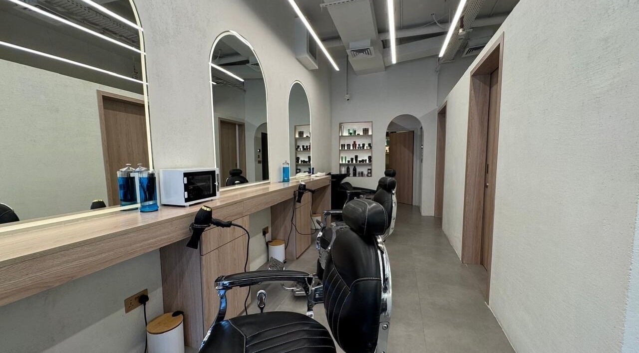 Modern interior of Black Oak Gents Salon in Dubai, Dubai, AE with stylish barber chairs and product shelves.