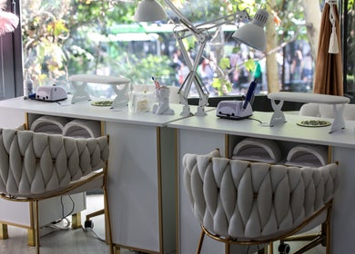 Interior modern al salonului Elysia Beauty Lounge București, București, RO, cu scaune elegante și mese de manichiură albe.