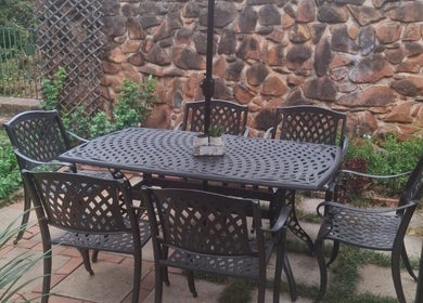 Relaxing patio with metal furniture at Flow By Ane, Pretoria, Gauteng, ZA, enveloped by lush greenery.