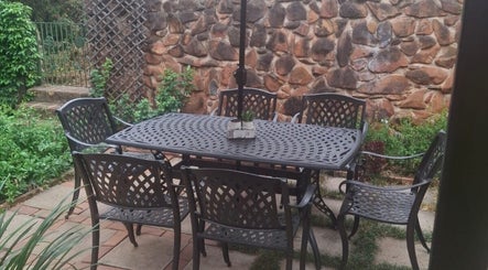Relaxing patio with metal furniture at Flow By Ane, Pretoria, Gauteng, ZA, enveloped by lush greenery.
