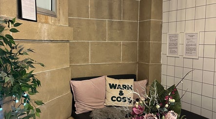 Relaxing nook at Bonnie Belle Nails, Glasgow, Scotland, GB, featuring soft cushions and vibrant floral decor.