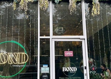 Stylish entrance at Bonnie Belle Nails, Glasgow, Scotland, GB featuring vibrant signage and greenery.