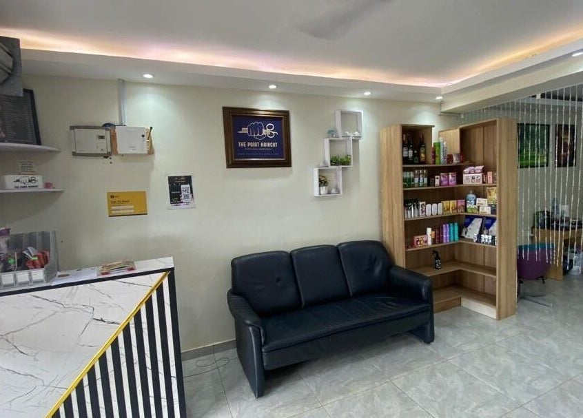 Reception area at The Point Haircut & Spa, Accra, showcasing a stylish waiting area and product display.