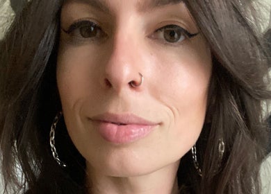Close-up of a woman with bold eyeliner and hoop earrings at Electric Beauty Co, Alameda, California, US.