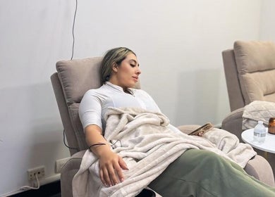 Woman relaxing in plush chair at Sueroterapia Medellín, a serene space in Medellín, Antioquia, CO.