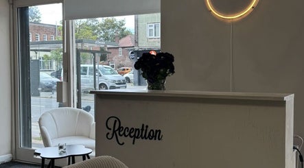 Reception area at Noa Beauty, Wythenshawe, with seating and a neon light.