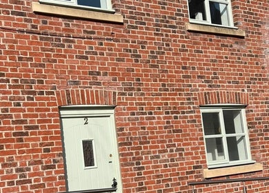 Brick facade of Sculpt&PoutPMU in Congleton, England, featuring white door and windows.