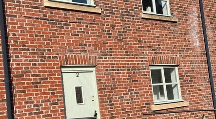 Brick facade of Sculpt&PoutPMU in Congleton, England, featuring white door and windows.