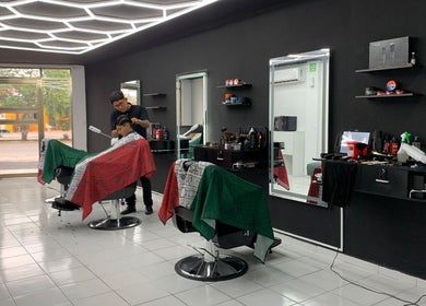 Interior moderno de barbería en Cancún, Quintana Roo, MX, cliente recibiendo corte de cabello profesional.