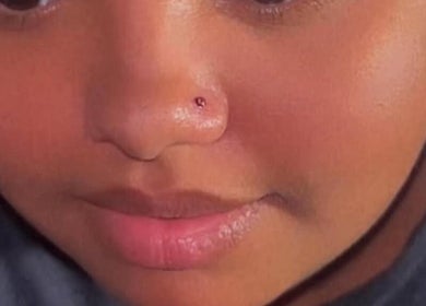 Close-up of a person's radiant skin with a nose ring at Kawaii Luxe Glow, Modesto, California, US.