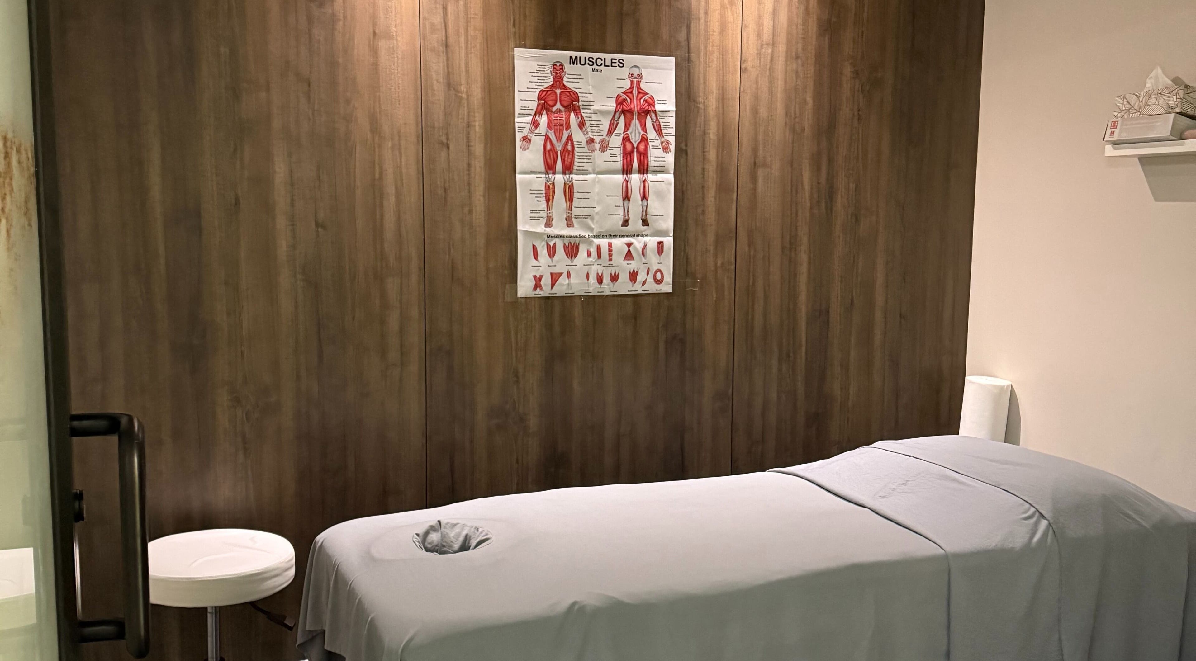 Massage room at Lumina Massage Wellness Center, Markham, Ontario, CA with a table and anatomy poster.