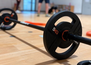 Close-up of gym barbell on wooden floor at MK Training, Holyport, England, GB, highlighting fitness facilities.