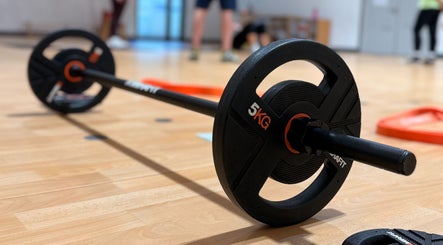 Close-up of gym barbell on wooden floor at MK Training, Holyport, England, GB, highlighting fitness facilities.