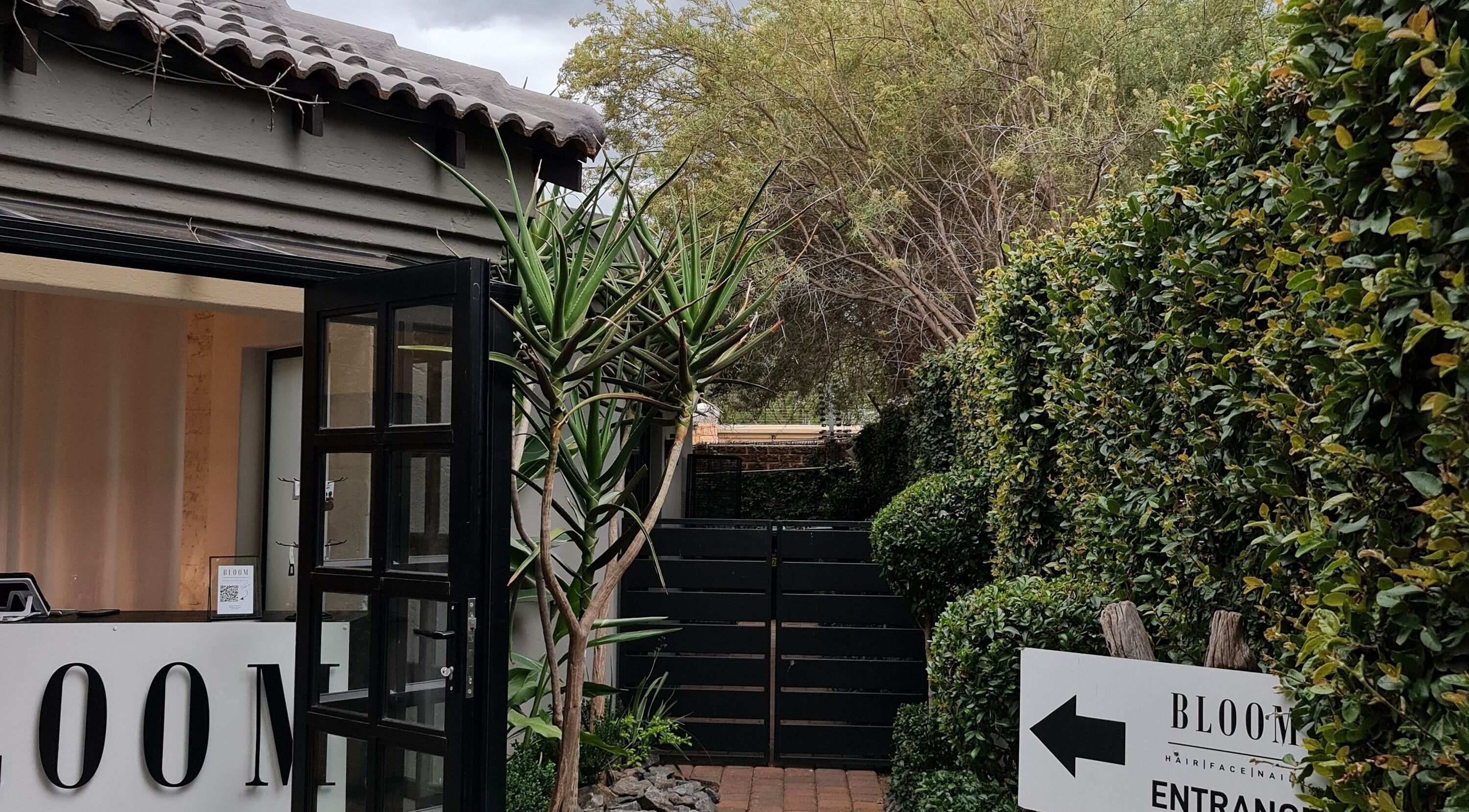 Entrance to Bloom_hair.face.nails at Silver Lakes Golf Estate, Gauteng, ZA, surrounded by lush greenery.