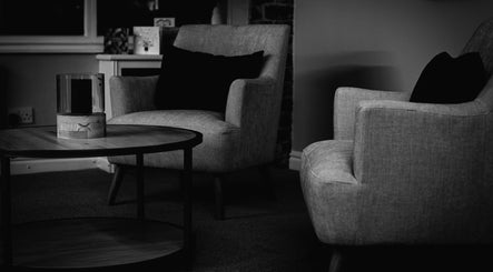Elegant seating area at Skin & Glo, Macclesfield, England, GB, featuring plush chairs and wooden coffee table.