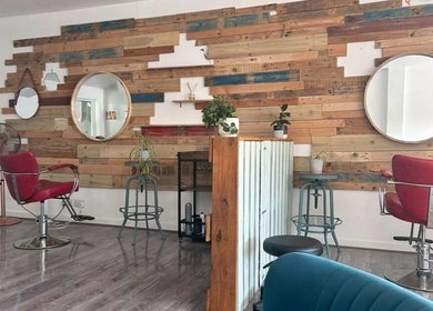 Chic interior of Tracey Jack Hair at Evolve in Newquay, England, GB with rustic mirrors and red chairs.