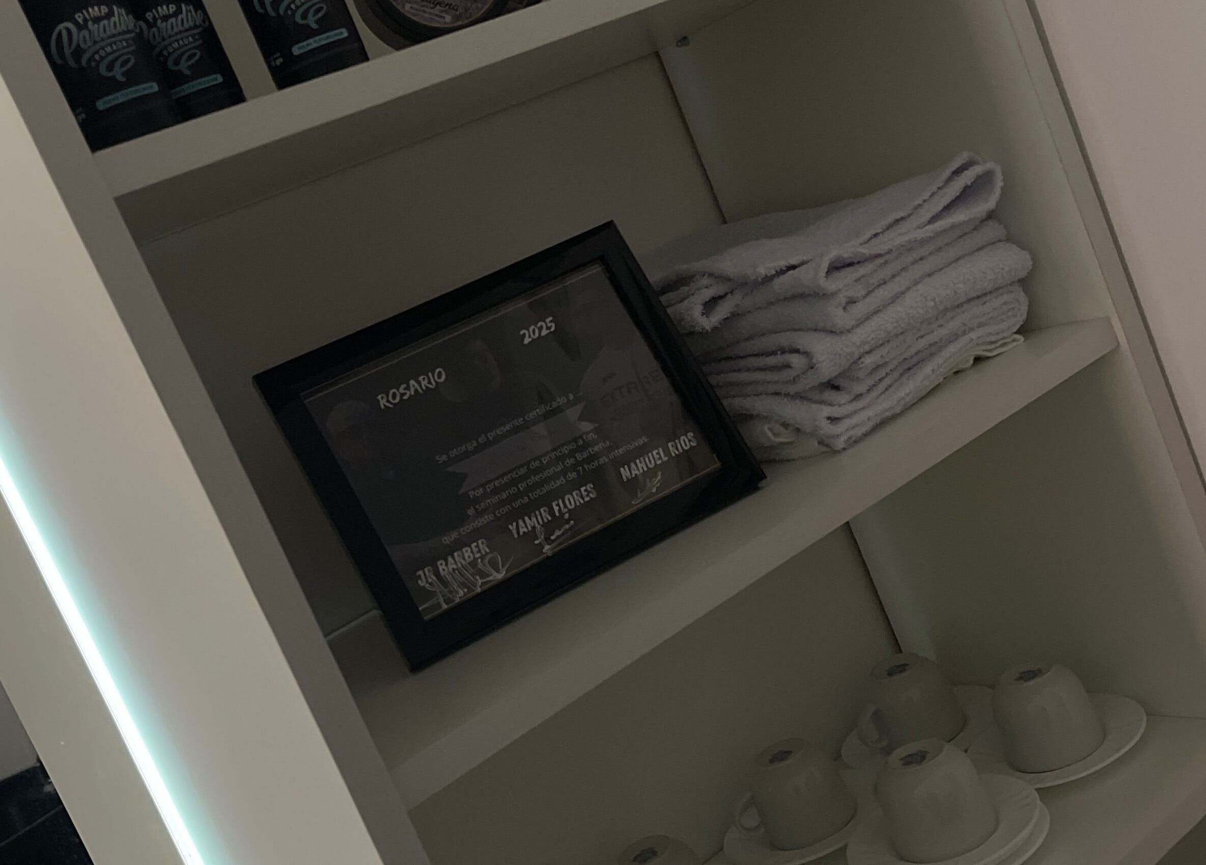 Leobarber shelf with products, towels, and cups in Rosario, Santa Fe, AR.