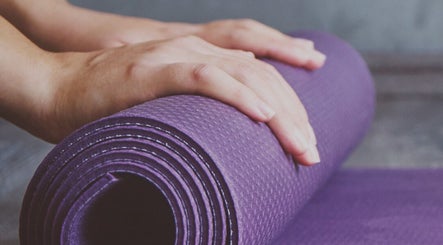 Hands prepare a purple yoga mat at FITLIVE, AE, setting a tranquil scene for wellness sessions.