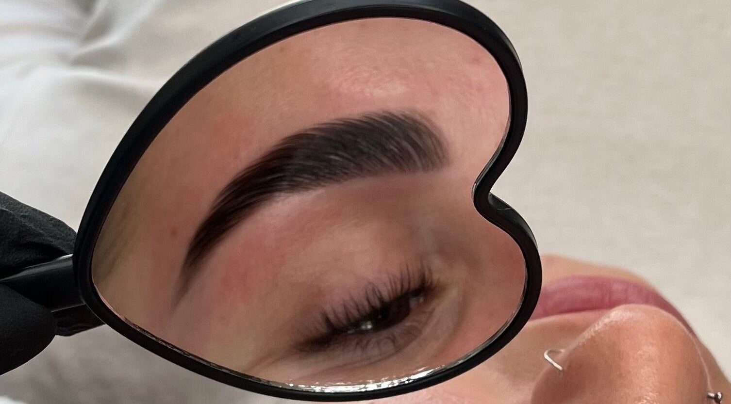 Eyebrow in heart-shaped mirror at Left & Right Beauty, Colchester, England, GB