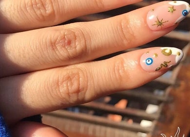 Elegant nail art featuring gold and blue charms at Estetica de belleza Soledad, Resistencia, Chaco, AR.