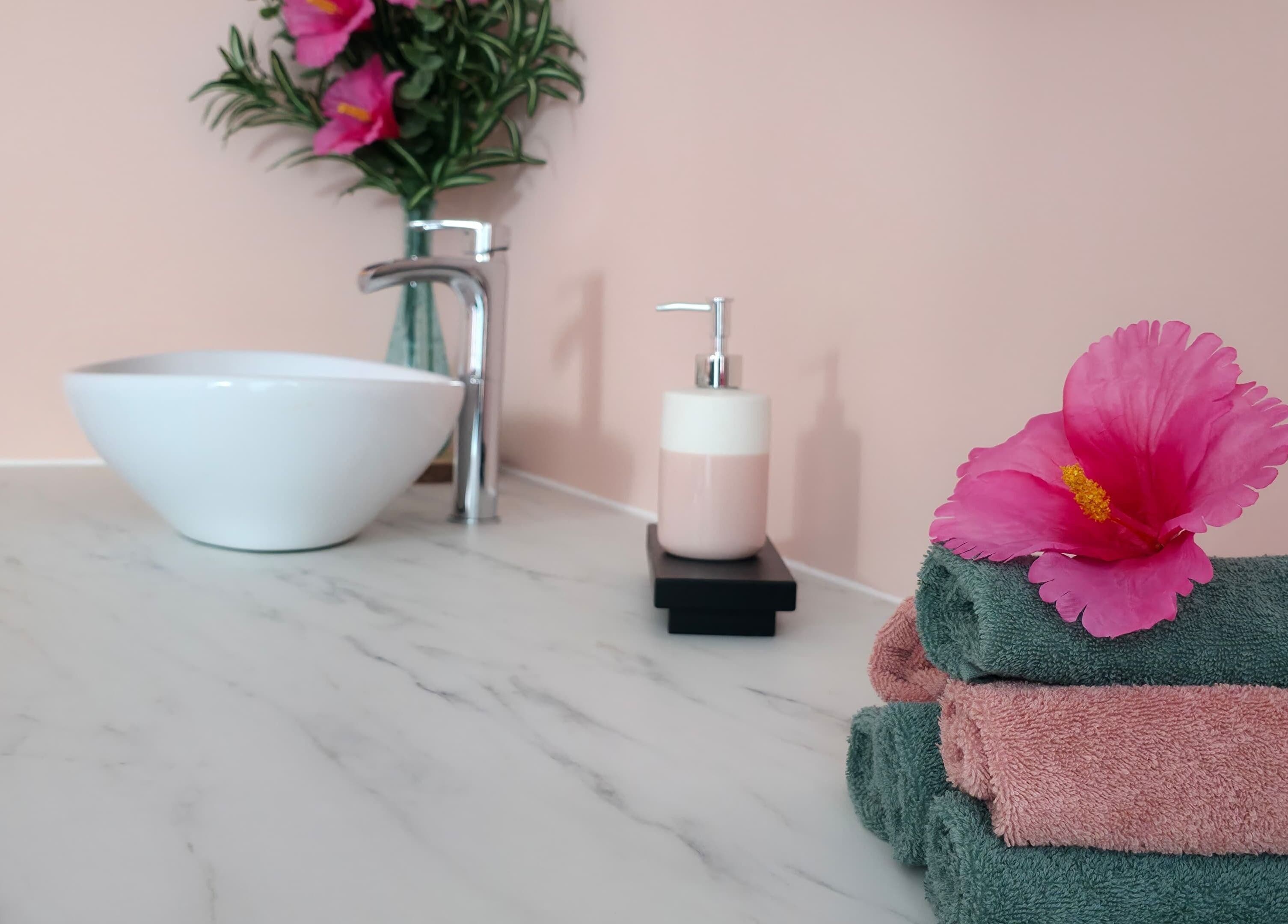 Espace de bien-être chez Clem's beauty à Rouen, Normandie, FR avec serviettes et fleurs exotiques.