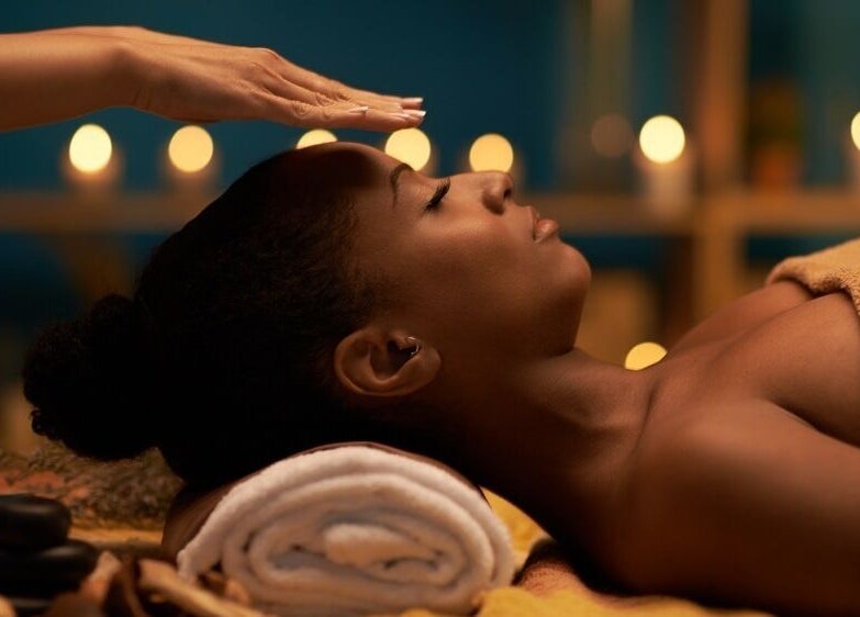 Client receiving a soothing forehead massage at Healing Hands in Gravesend, England, GB, surrounded by candles.