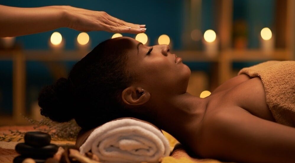 Client receiving a soothing forehead massage at Healing Hands in Gravesend, England, GB, surrounded by candles.