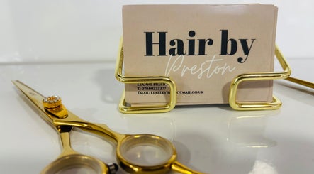 Gold scissors beside Hair by Preston's sleek cardholder in Taunton, England, GB.