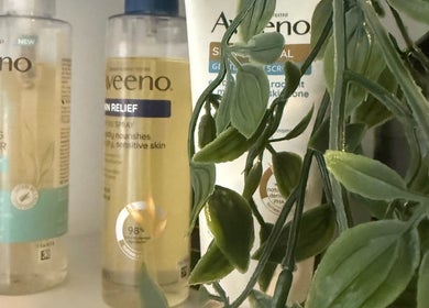 Aveeno skincare products on shelf at Vive Contour, Bexleyheath, England, GB with green plant decor.