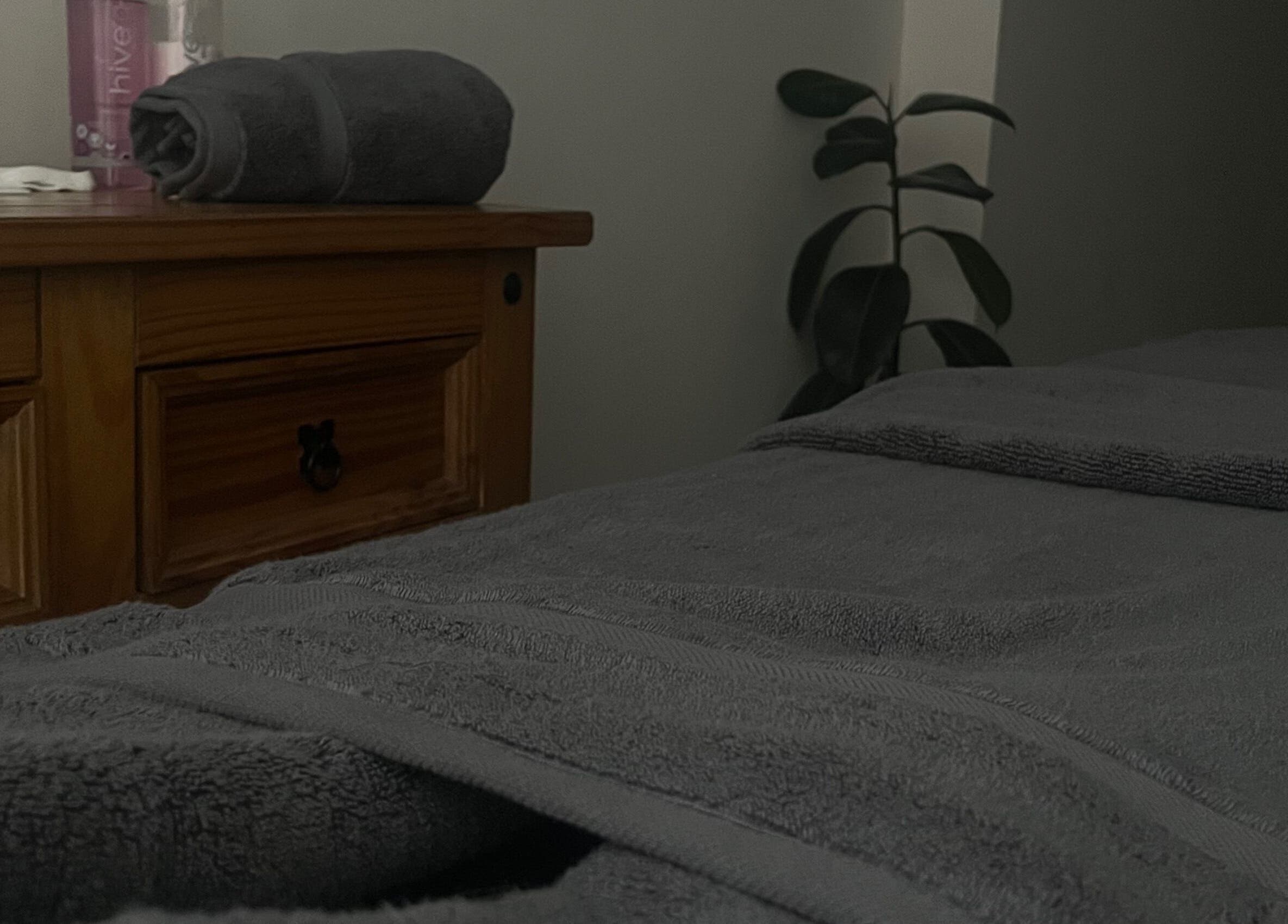 Cozy treatment room at Rejuvenate.br, Layer De La Haye, England. Soft towels on a wooden dresser.