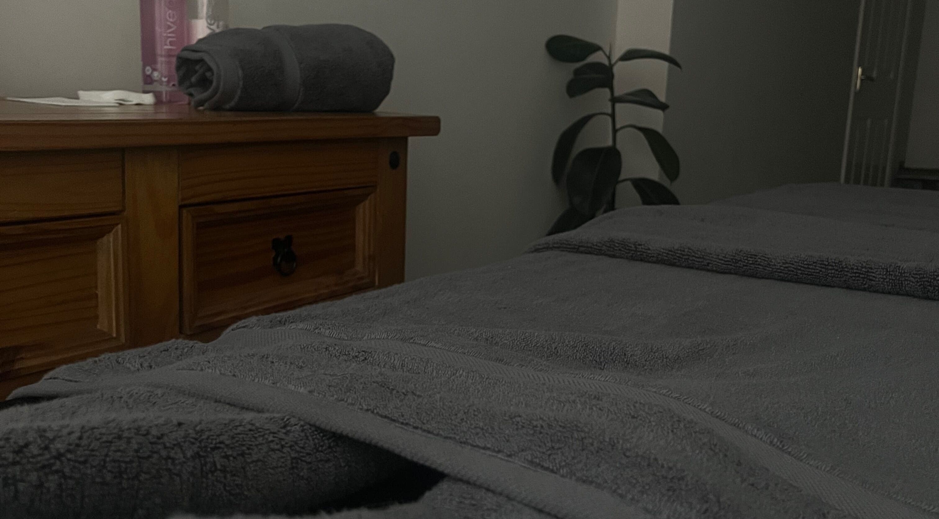 Cozy treatment room at Rejuvenate.br, Layer De La Haye, England. Soft towels on a wooden dresser.