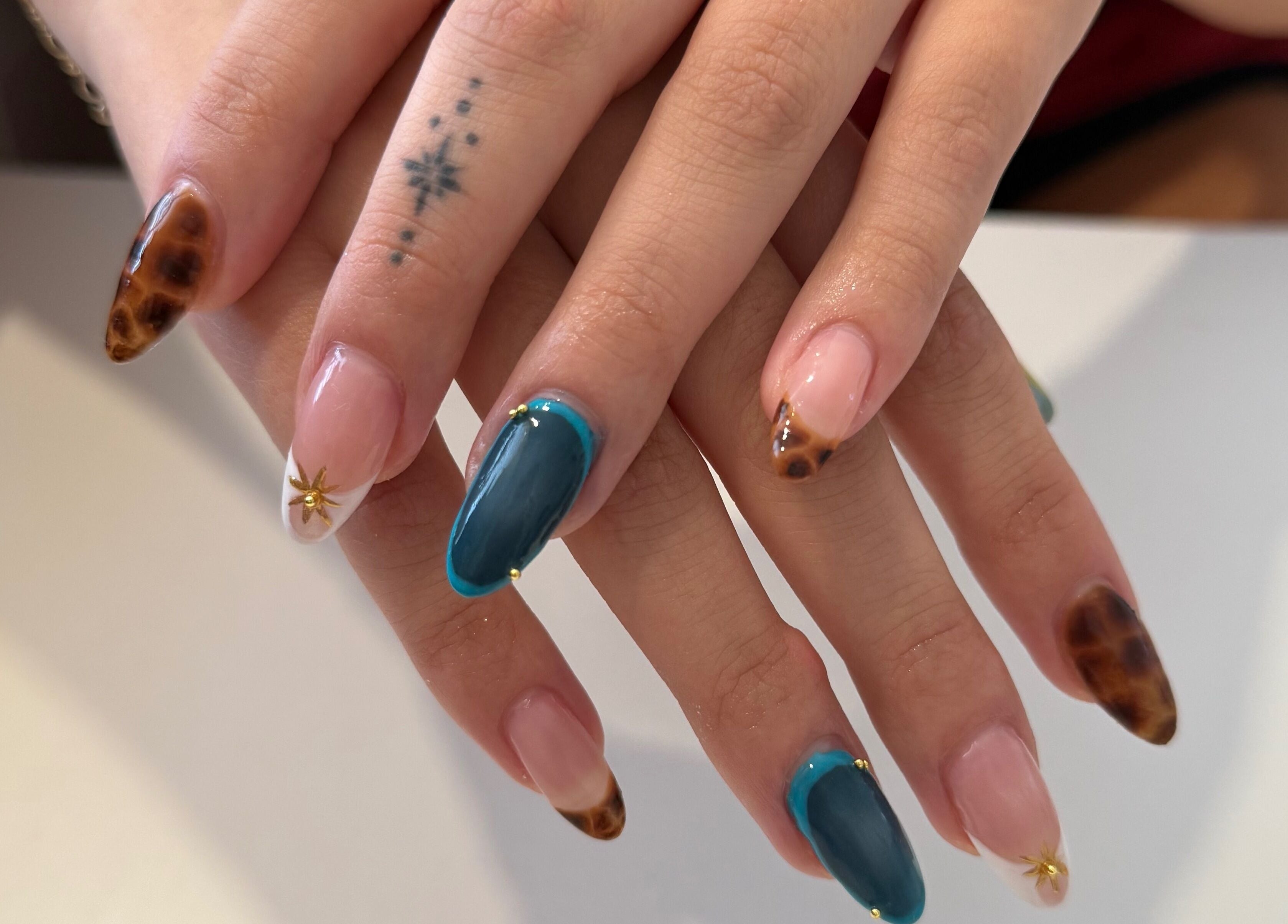 Unique nail art design at Melia Nailed It, Tucson, Arizona, US. Features star patterns and mixed colors.