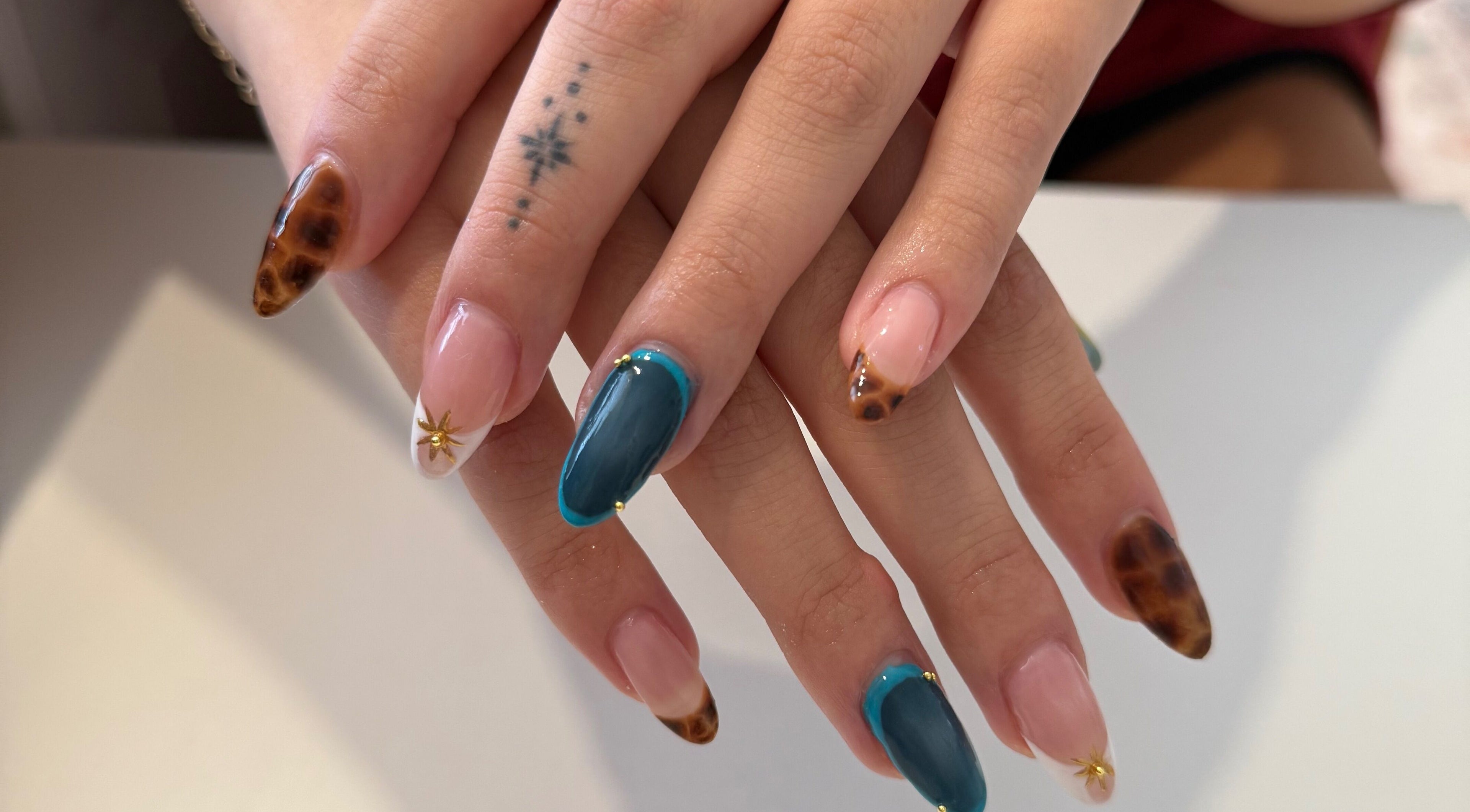 Unique nail art design at Melia Nailed It, Tucson, Arizona, US. Features star patterns and mixed colors.