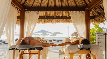 Couple enjoying a beachfront massage at Purun Spa, Eagle, AW under a thatched cabana.