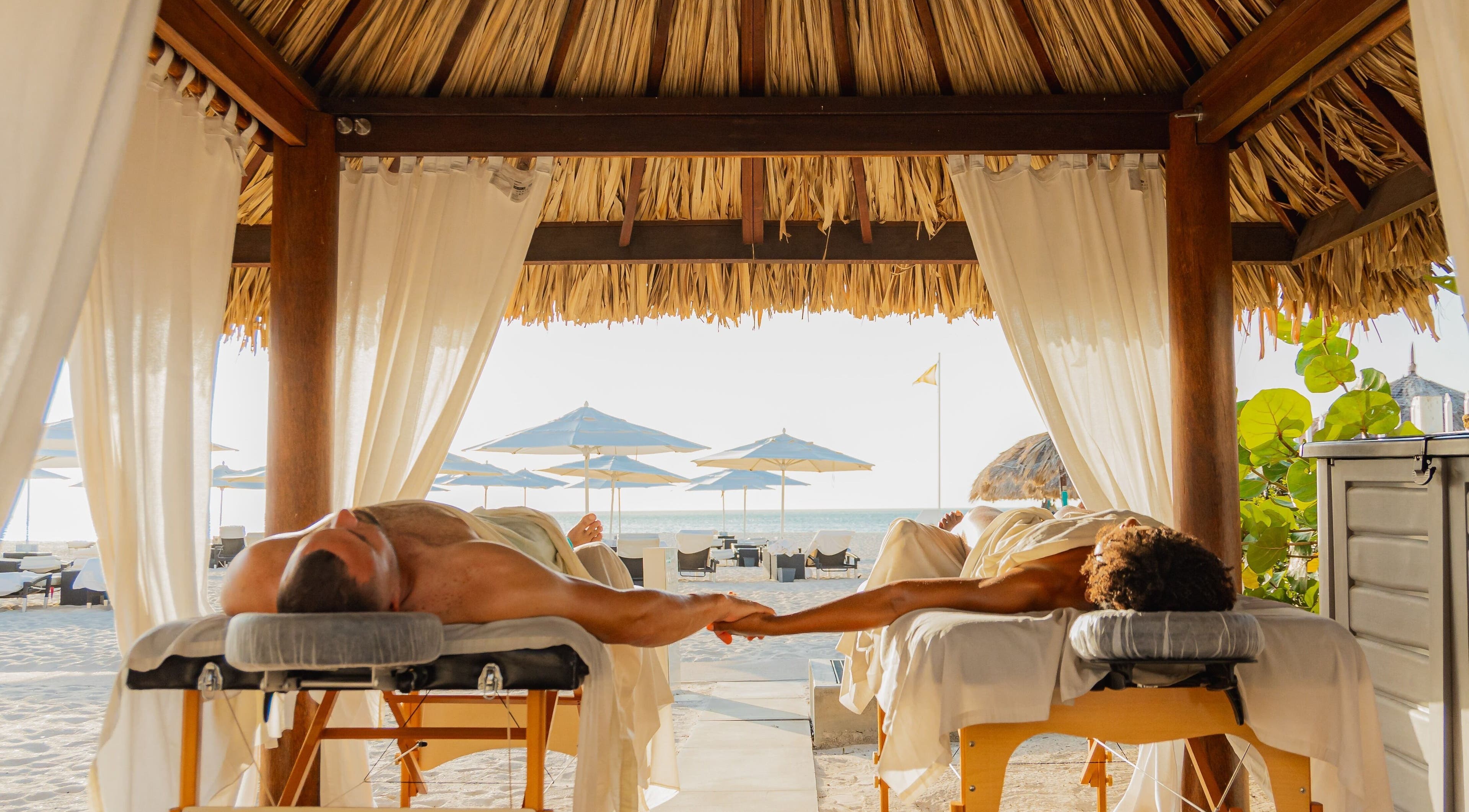 Couple enjoying a beachfront massage at Purun Spa, Eagle, AW under a thatched cabana.