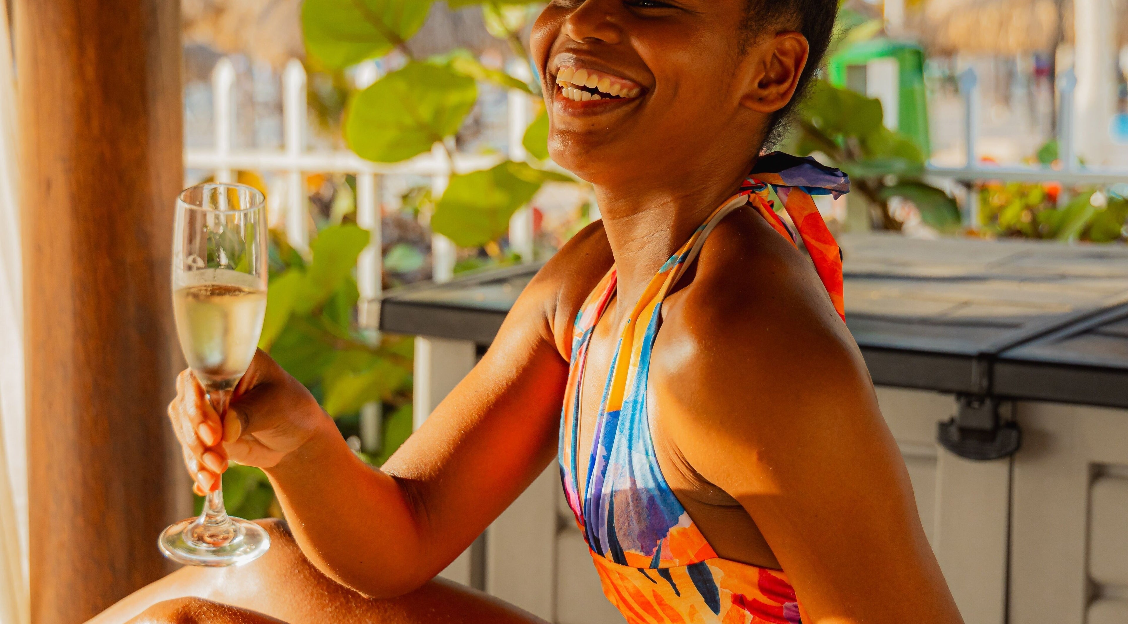Smiling woman enjoying champagne at Purun Spa, Eagle, AW amid lush greenery.