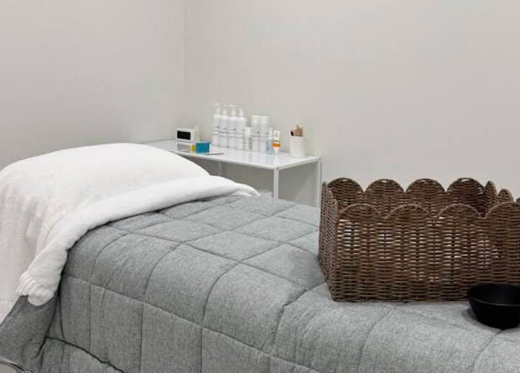 Cozy treatment room at Glow Aesthetics Collective, Ingle Farm, South Australia, AU with spa bed and wicker basket.