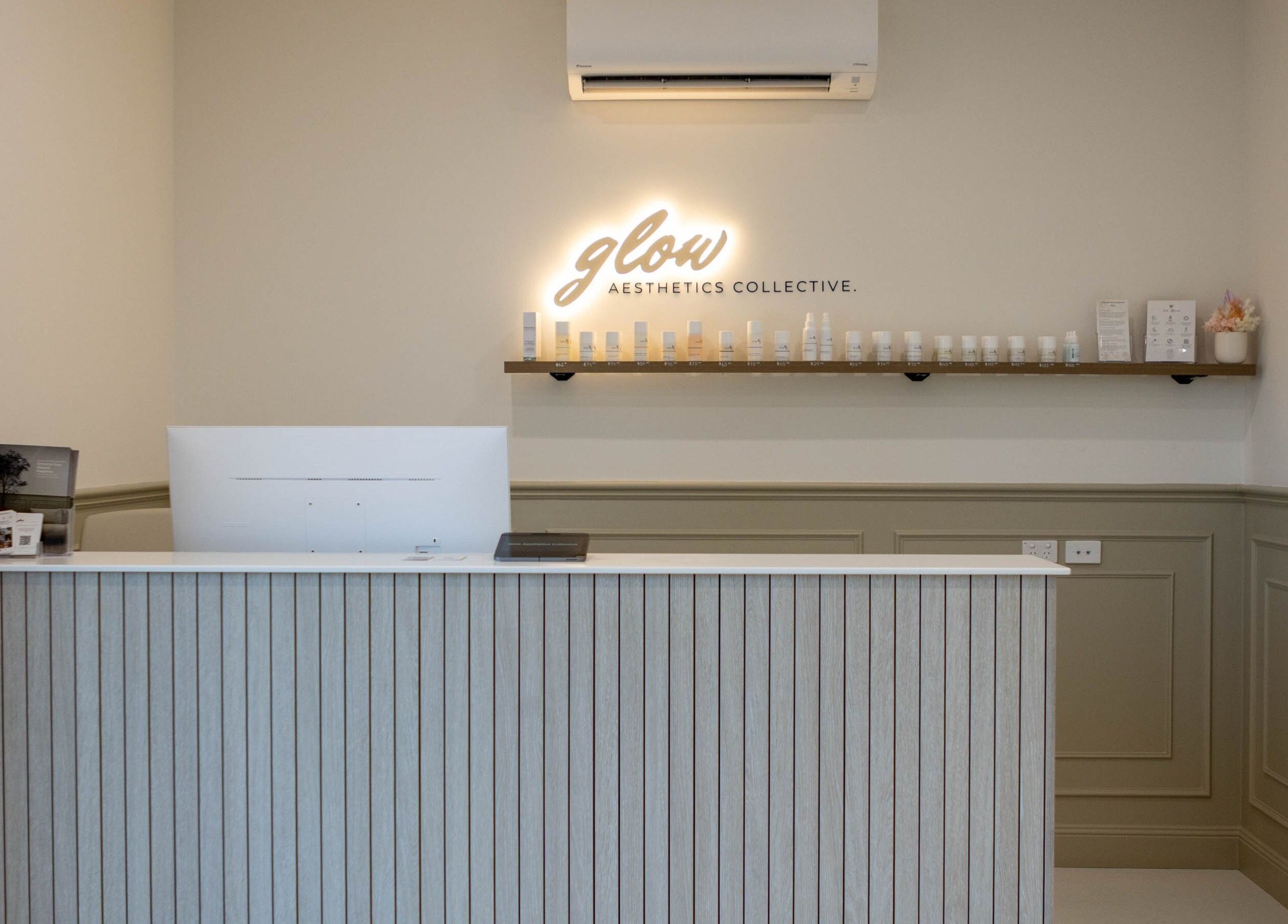 Reception desk at Glow Aesthetics Collective, Ingle Farm, South Australia, AU, with elegant decor and skincare products.
