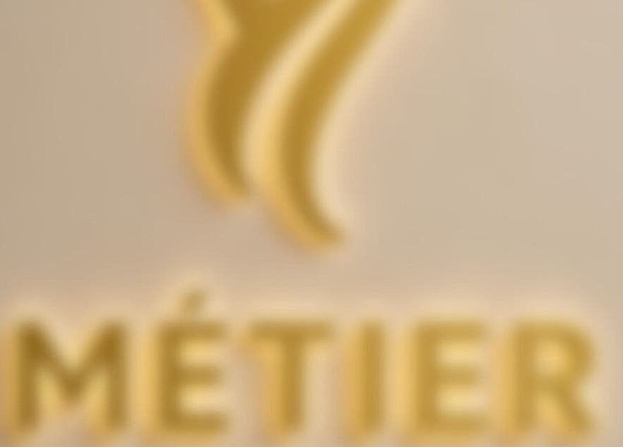 Blurry golden logo of METIER HAIR SPECIALIST at Standish, England, GB.