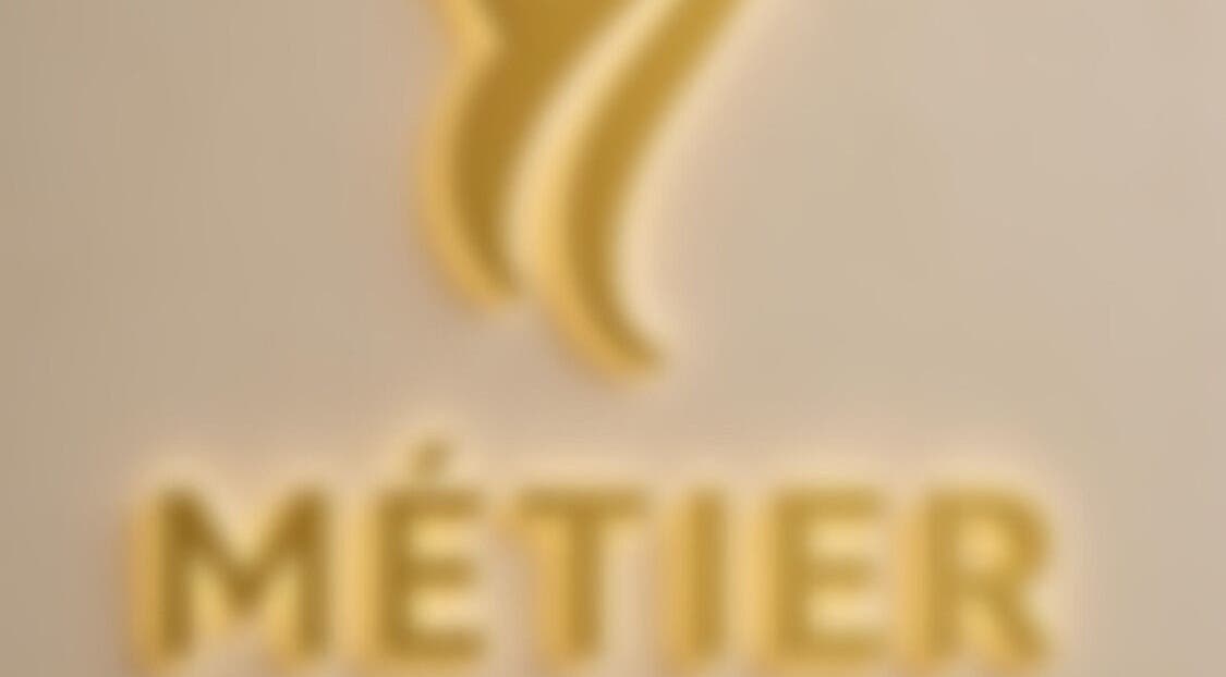 Blurry golden logo of METIER HAIR SPECIALIST at Standish, England, GB.