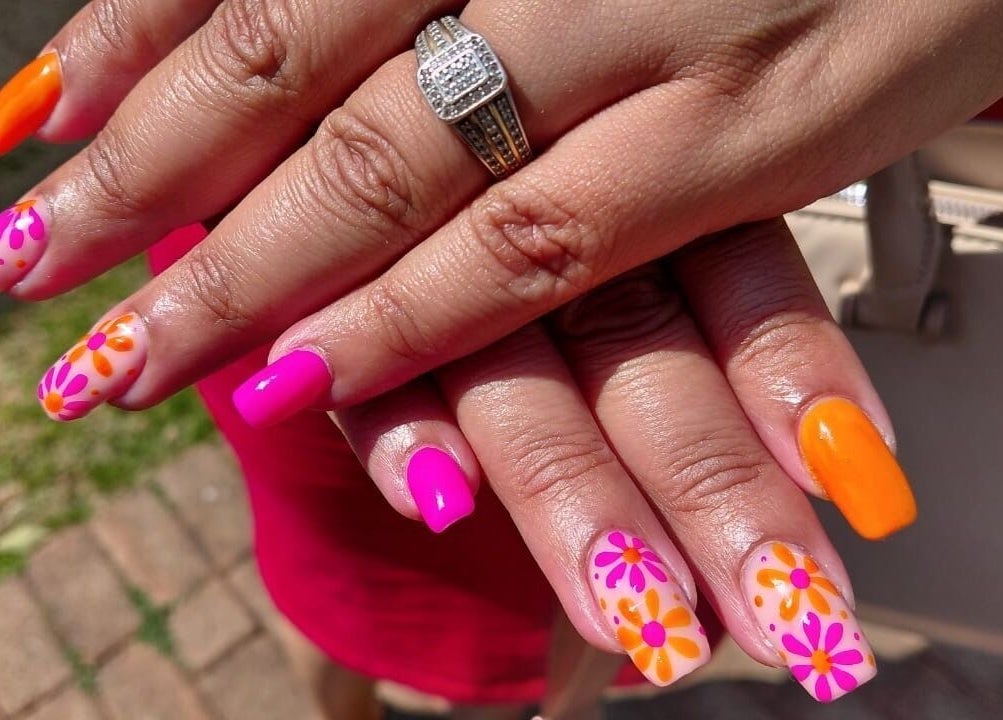 Vibrant floral nail art at Nails By Shaaquila, Roodepoort, Gauteng, ZA. Bright orange and pink designs.