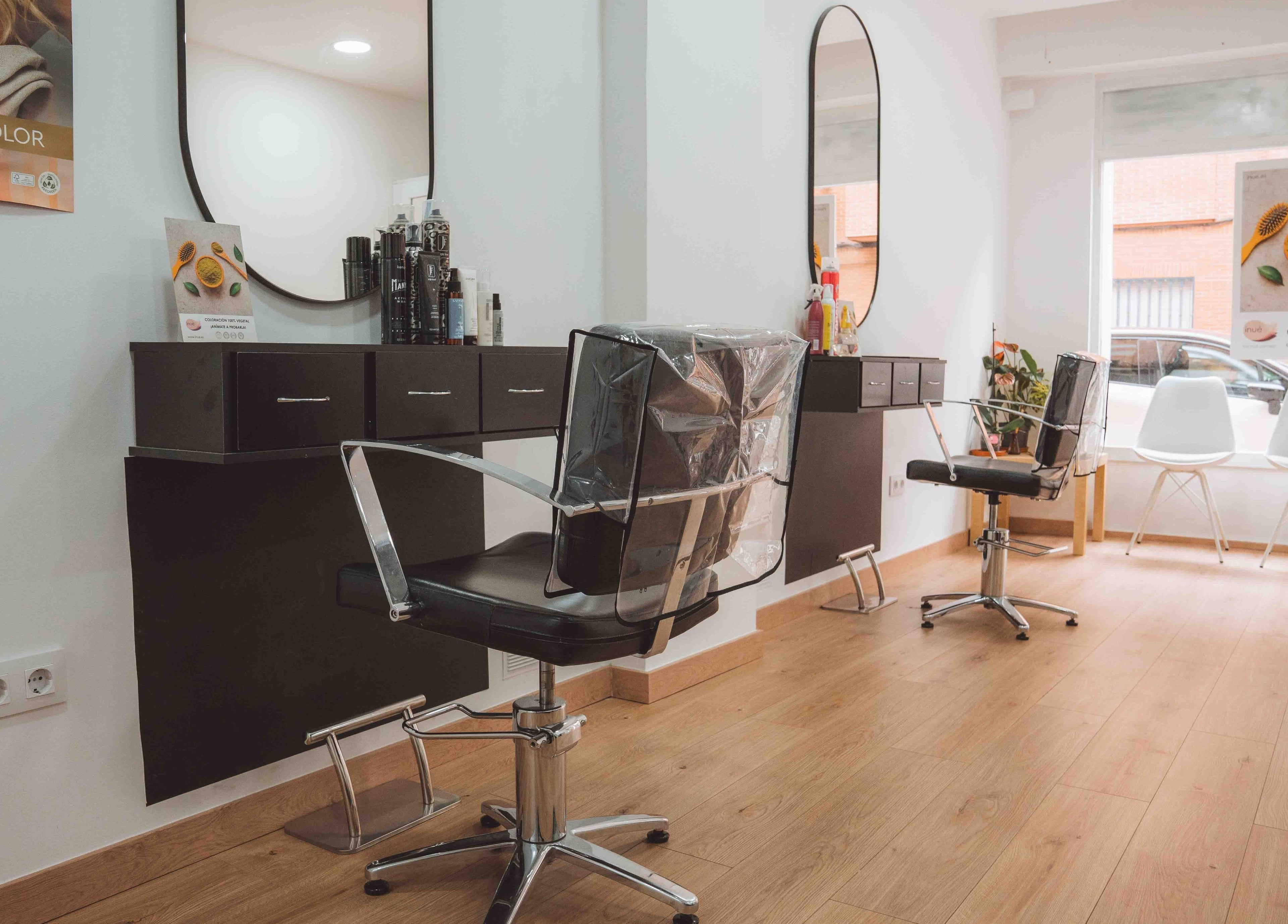 Moderno salón de M'AS PELUQUEROS en Madrid, Comunidad De Madrid, ES, con sillas elegantes y espejos ovalados.