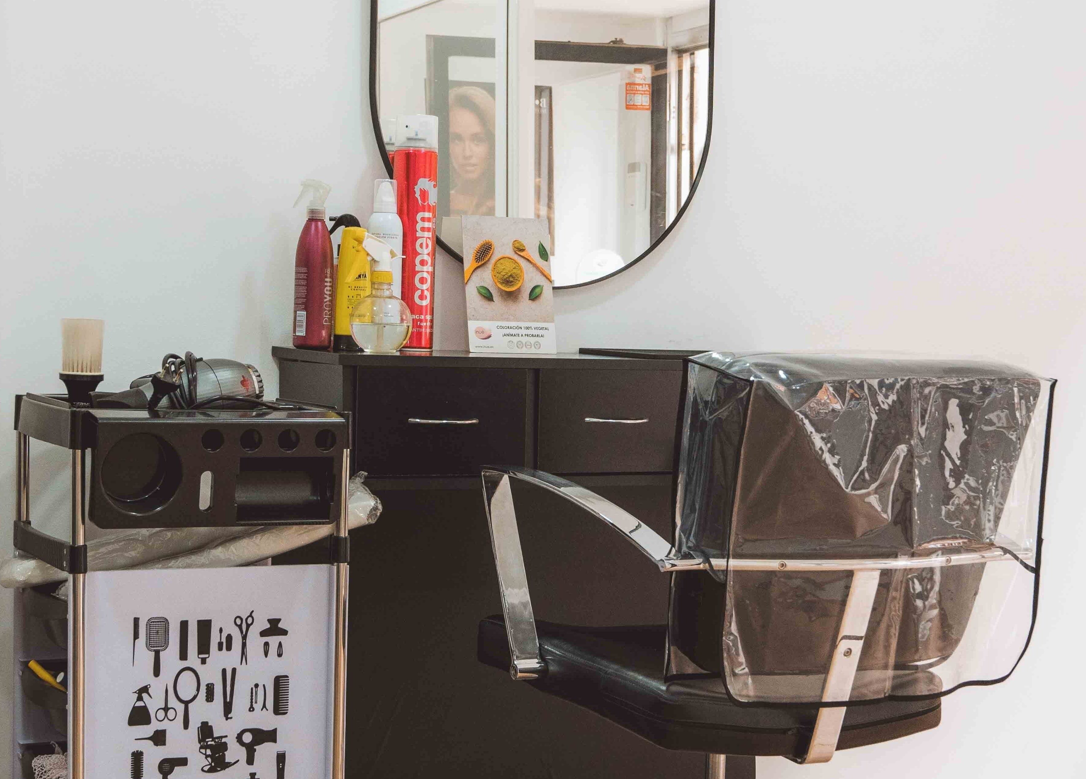 Interior de M'AS PELUQUEROS en Madrid, Comunidad De Madrid, ES con silla de peluquería y productos de belleza.