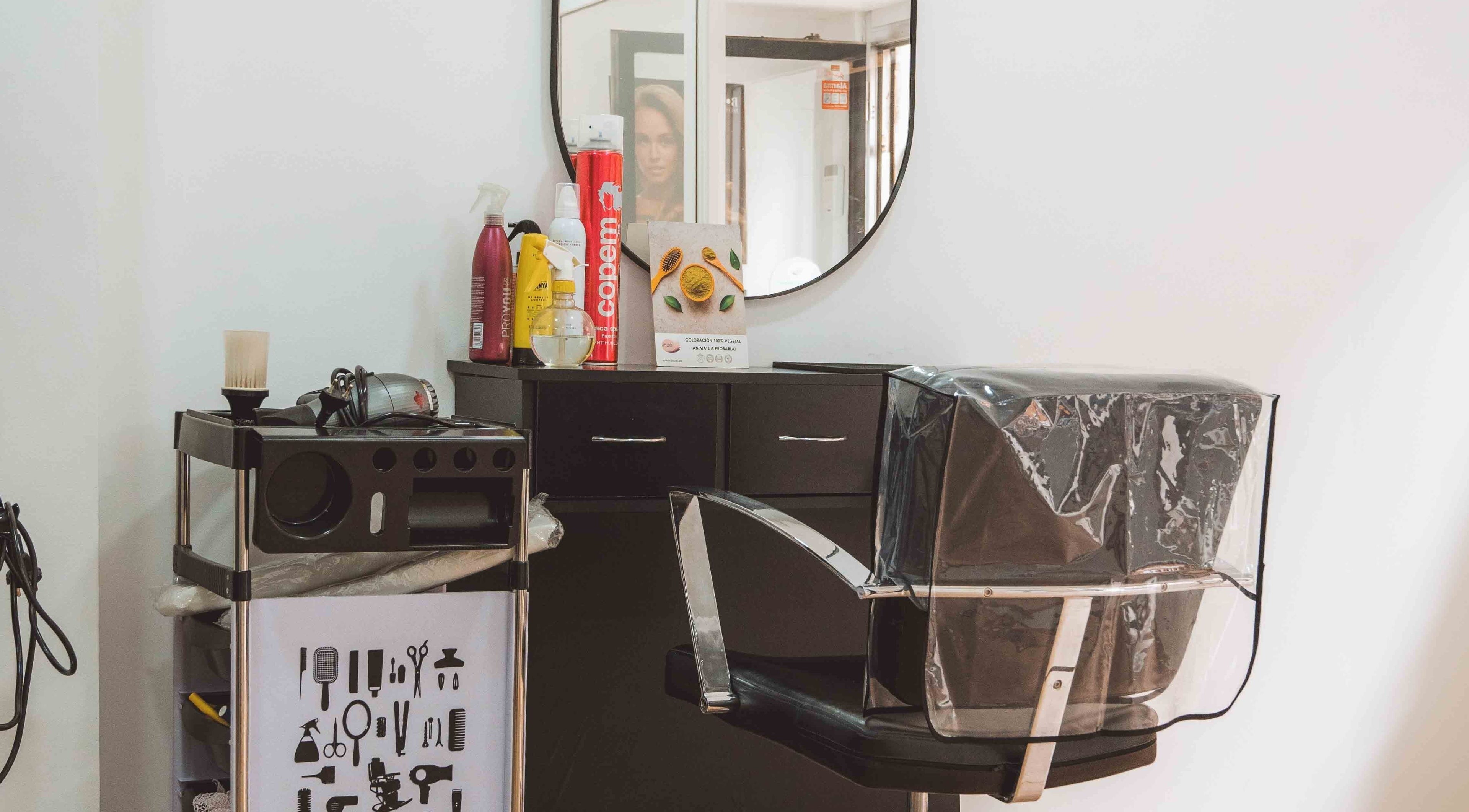 Interior de M'AS PELUQUEROS en Madrid, Comunidad De Madrid, ES con silla de peluquería y productos de belleza.