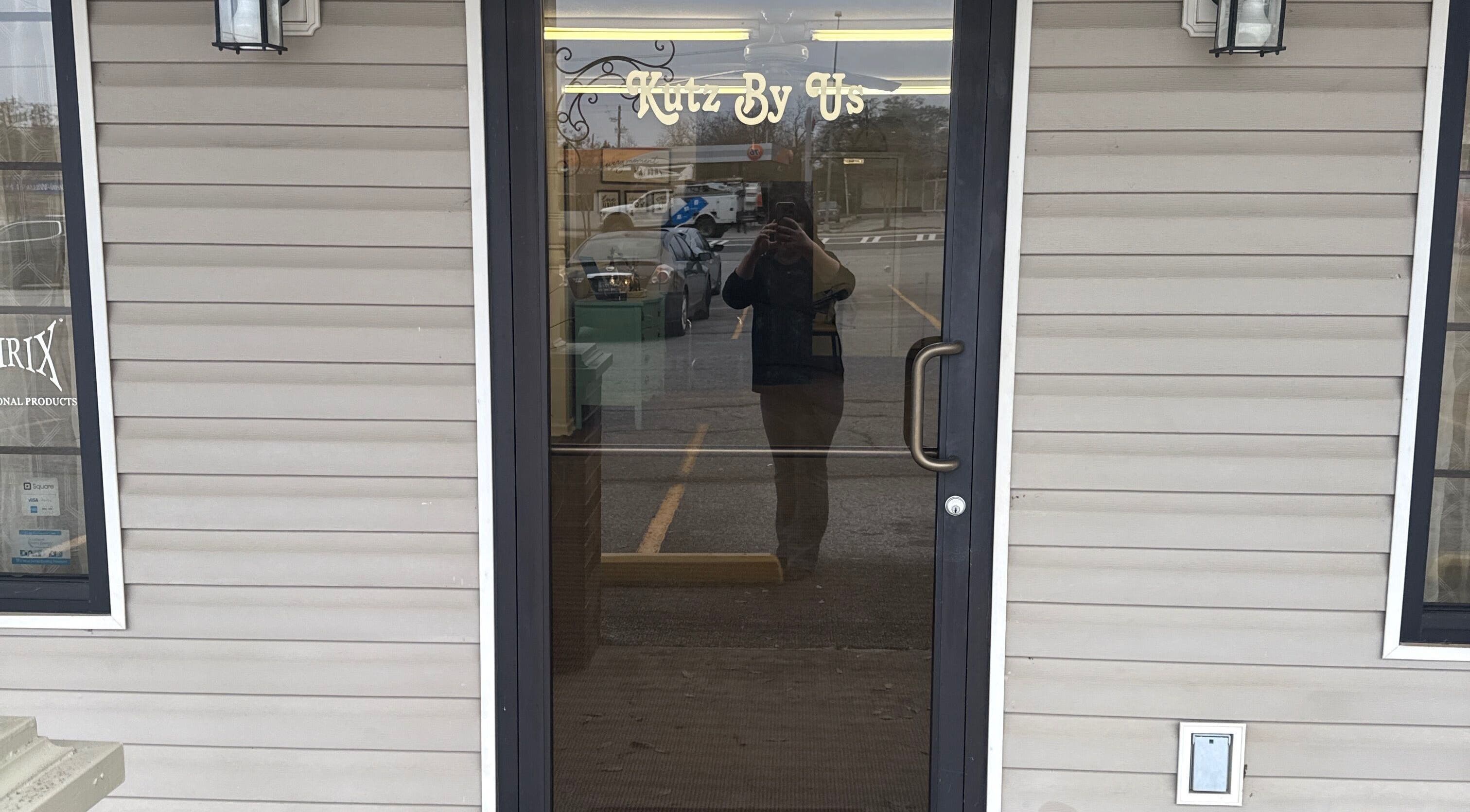 Front door of Kutz By Us in Thomaston, Georgia, US, showcasing elegant signage and inviting entrance.