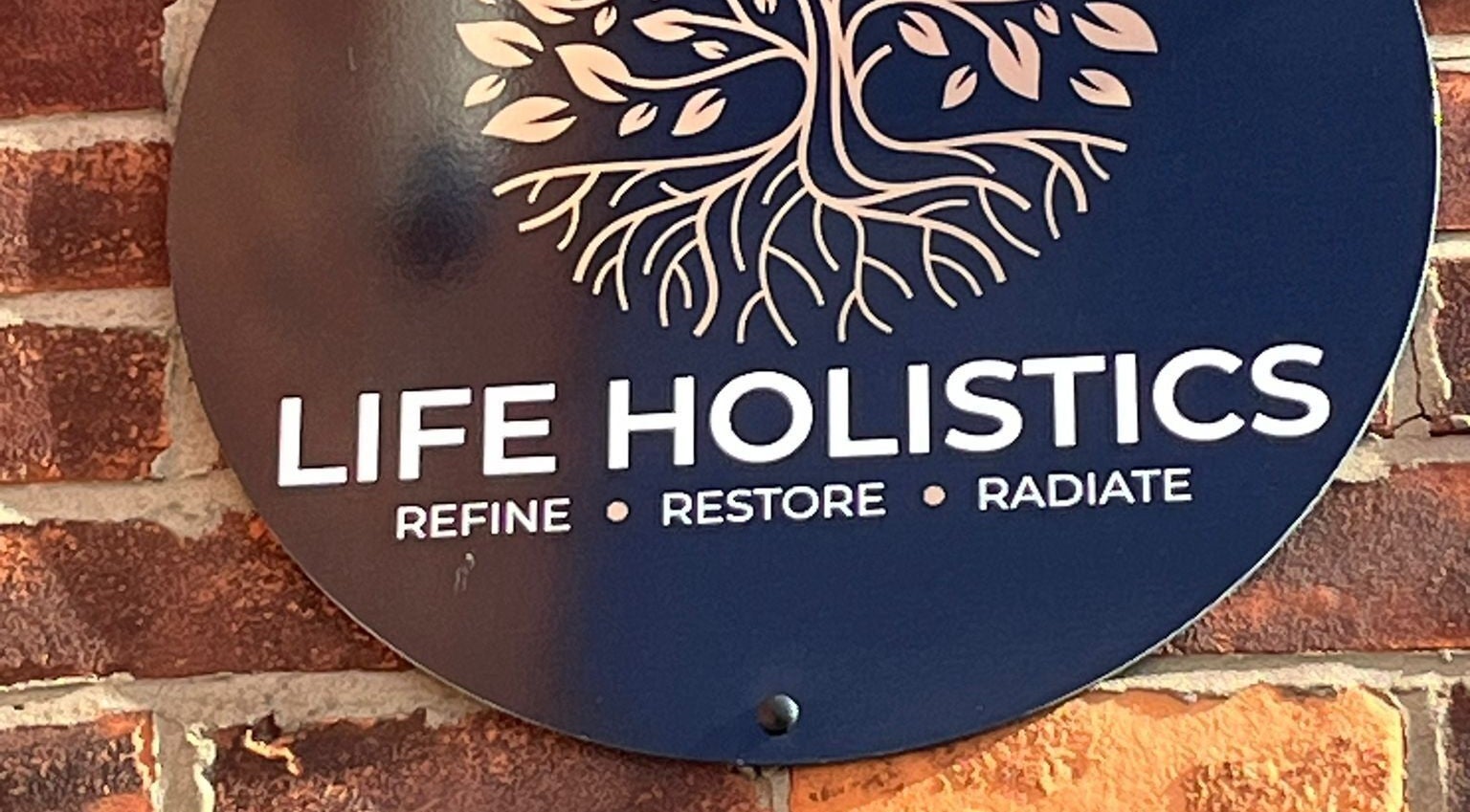 Life Holistics sign on a rustic brick wall in North Shields, England, GB.