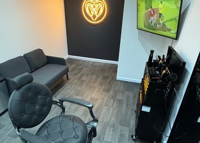 Chic interior of Snakebite Barbers in Hartlepool, England, GB featuring a plush sofa and modern barber chair.