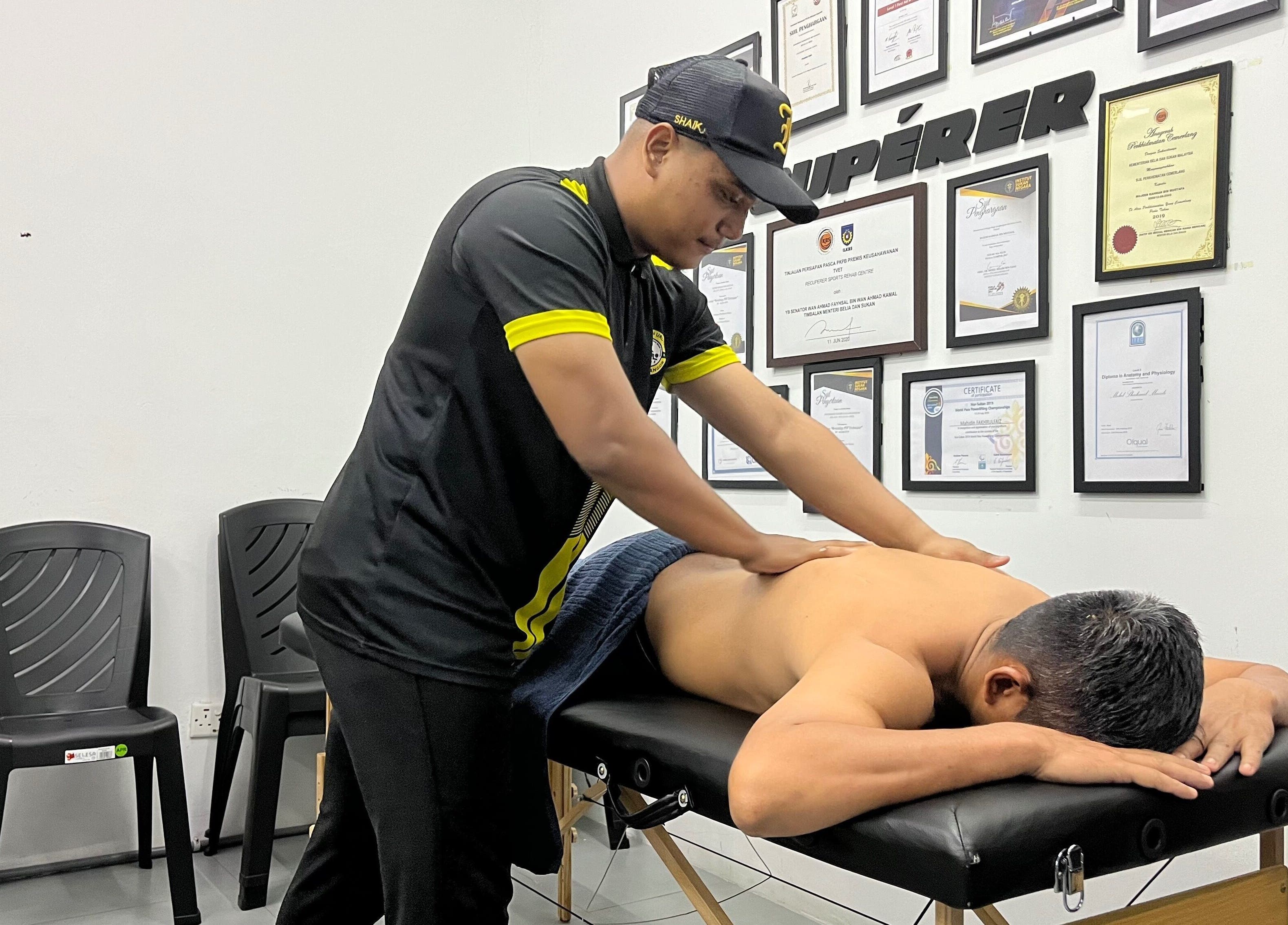 Skilled therapist performs massage at MAMU MASSAGE, Shah Alam, Selangor, MY. Walls adorned with certifications.